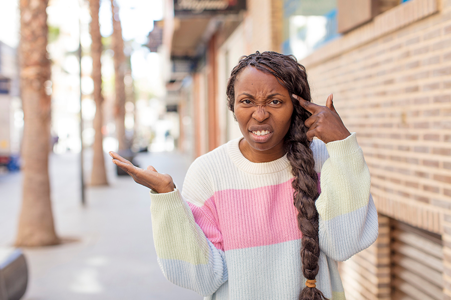 Eine Frau mit langem schwarzem Zopf und gestreiftem Pullover zeigt mir mit einer Grimasse einen Vogel